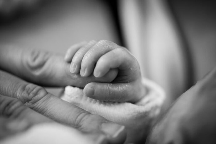 Mãe segurando a mão de um bebê para ilustrar para que serve a certidão de inteiro teor